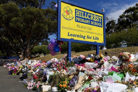 A yellow sign for a school surrounded by flowers.