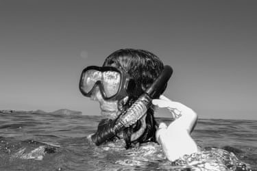 A woman’s head, wearing goggles and a snorkel, above the seawater