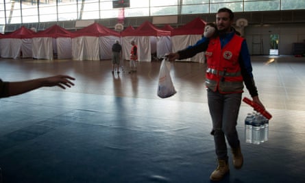 A French Red Cross volunteer hands out aid in a sports hall being used as a makeshift shelter.