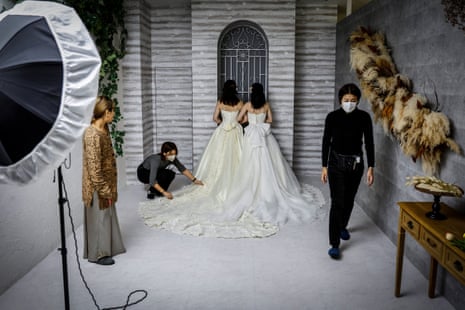 A bisexual-lesbian couple in wedding dresses in a studio