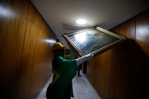 A worker carrying a framed artwork in a corridor of Brazil's Presidential Palace