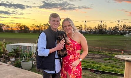 A miniature dachshund in the arms of a man and woman