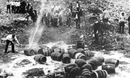 Beer barrels are destroyed by prohibition agents in an unknown location.
