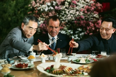 Nixon holds his chopsticks in the ready position as Zhou (left) and Shanghai Communist Party leader Chang Chun-chiao reach in front of him