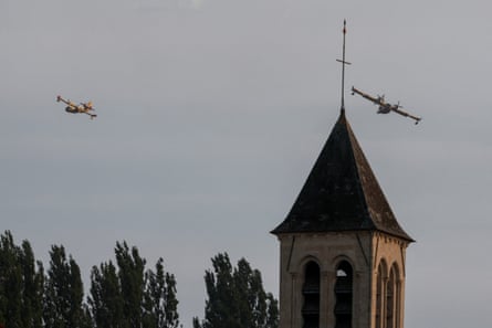 Firefighting planes fly above church steeple and trees