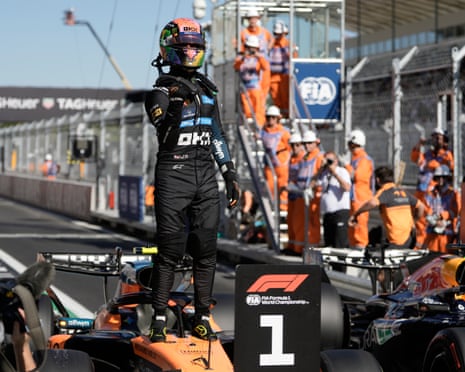 Lando Norris stands on top of his car celebrating pole position near a "1" marker