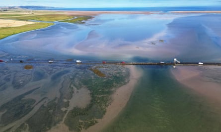 Vehicles travel along Holy Island causeway.