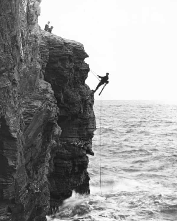 Cherry Kearton dangling precariously from a rock face