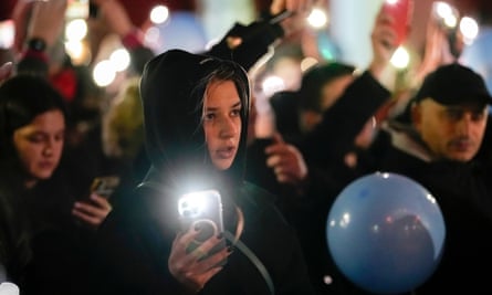 young and old people hold up phones with torches on
