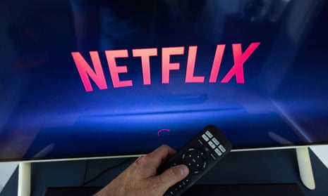 Person holding a TV remote to turn on Netflix