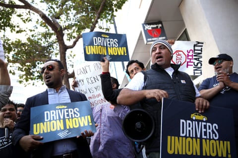 Rideshare drivers wave flags and hold signs during a protest outside Uber headquarters last year.