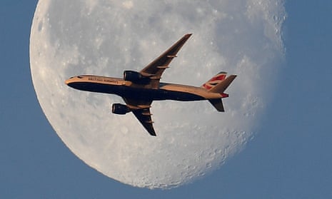 A British Airways passenger plane flies in front of the moon