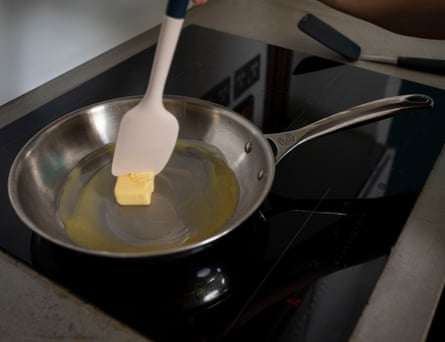 Le Creuset stainless steel frying pan with butter and a silicon spatula melting.