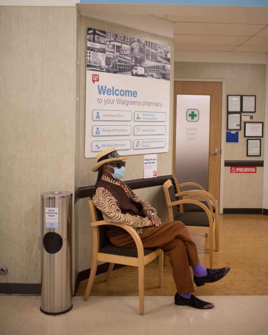 The bluesman at a local Walgreens waits to get a Covid vaccine. His outfit – a pointed hat, shades, and a sharp brown waistcoat – is again at odds with the sterile surroundings.