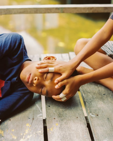 A child’s head is cradled in the hands of another child