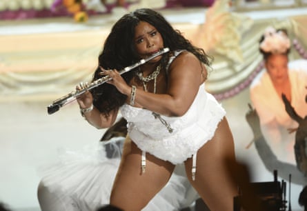 Lizzo on stage, playing the flute, in 2019.