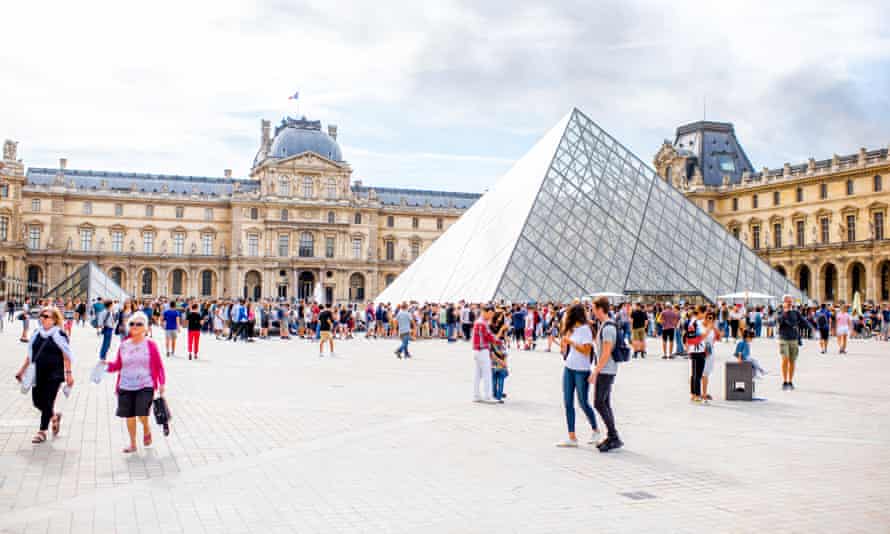View on the Louvre museum square, Paris full of people during the cloudy weather.