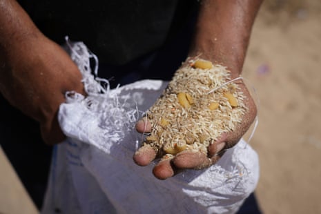 A Palestinian man displays the contents of humanitarian aid packages after they were airdropped into Zawaida, in the central Gaza Strip on Wednesday, July 30, 2025.