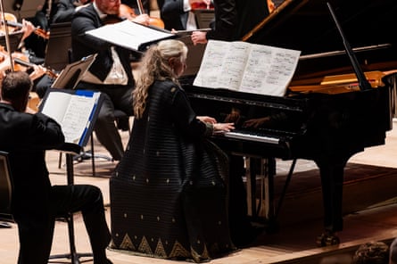 A woman playing piano in a large orchestra.
