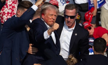 Donald Trump, surrounded by secret service agents, punches the air