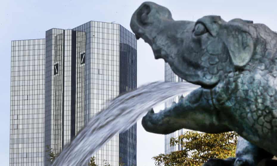 Water spills out of a small dragon sculpture on a fountain with the headquarters of the Deutsche Bank in background in Frankfurt, Germany.