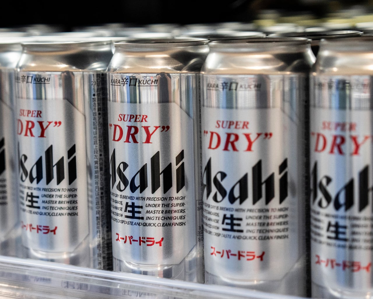 Rows of silver "Super Dry" Asahi beer cans displayed closely together on a supermarket shelf