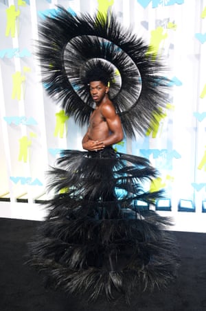 Lil Nas X on the VMAs carpet. He is wearing a circular black headdress and a feathery black skirt over black pants