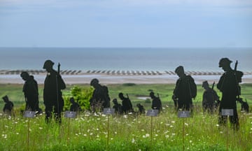 Artworks of silhouettes of soliders placed across a beach in Normandy