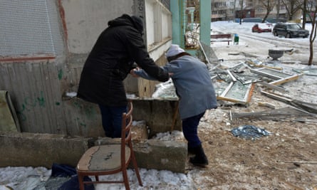 A man helps a wounded woman to a building’s basement for shelter in Kharkiv on Sunday.