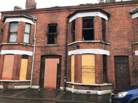 Fire-damaged terrace houses with boarded up windows on the ground floor