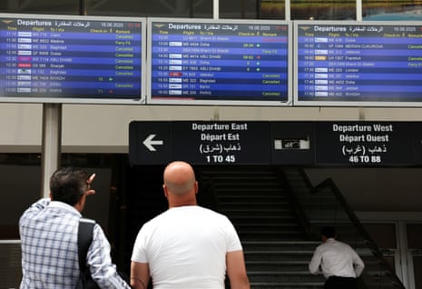 People check flight information display screens showing information about cancelled flights at the Beirut-Rafic Hariri Airport, Lebanon June 16, 2025.
