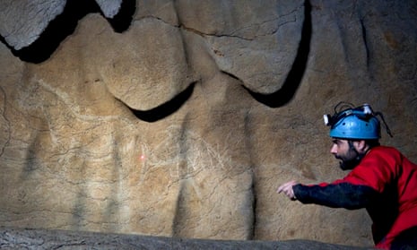 Archaeologist Diego Garate looking at cave paintings representing horses in the Atxurra cave.
