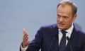 Donald Tusk gestures as he stands behind two microphones at a press conference