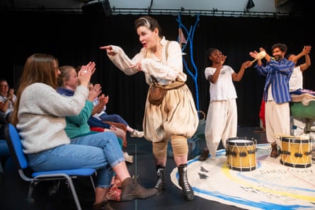 A woman in character as a man points to audience members.