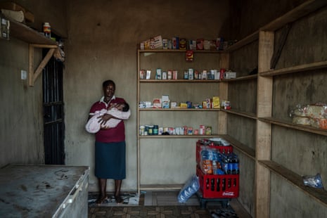 A woman stands in a small room with medicine on the shelves. 