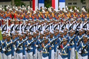 Rows of male and female Indonesian soldiers in colourful outfits take part in a welcome ceremony for France’s president, Emmanuel Macron