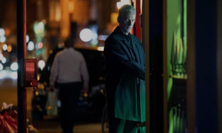 Peter Capaldi in a scene from Criminal Record, seen almost full-length standing on a dark street looking round.