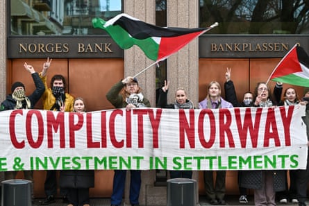 Protesters with a sign saying Complicity Norway wave Palestinian flags