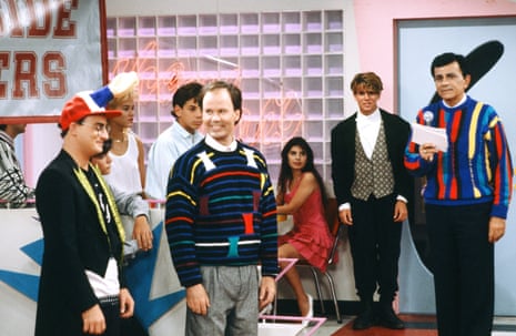 group of characters stand and sit on the set of a tv show
