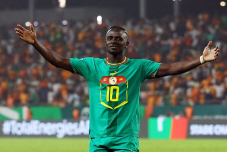 Sadio Mané, the Senegal forward wearing No 10, celebrates scoring a goal for his country at the Africa Cup of Nations by standing before the fans with his arms spread wide.