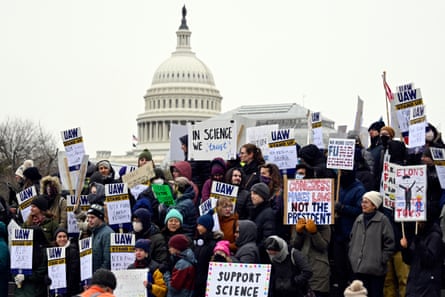 People rally near the US capitol and hold signs that say “support science”