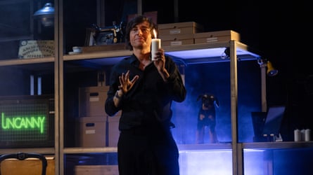 He stands in a warehouse-style set, holding a church candle