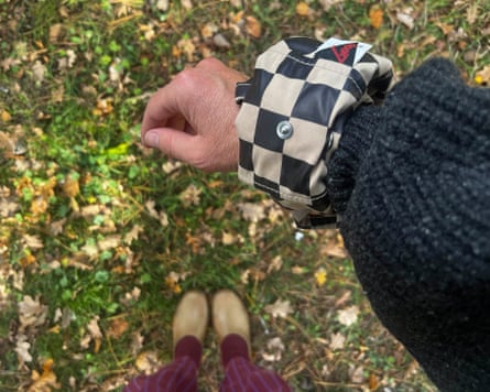 A woman wearing a black and tan checked cuff over a knitted sleeve, with brown clogs below