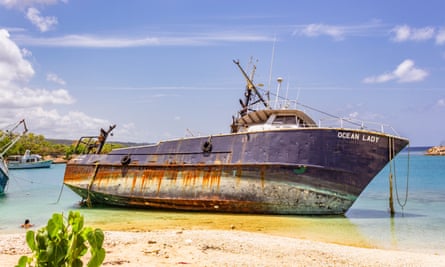 A grounded ship leans to the right with her entire hull exposed by the receding water
