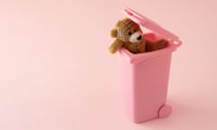 A teddy bear in a pink wheelie garbage bin against a pink background