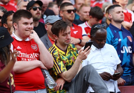 19 May 2024Arsenal fans at Emirates Stadium check their phones and discover Manchester City’s Phil Foden has scored an early goal on the final day of the season. Arsenal beat Everton 2-1.