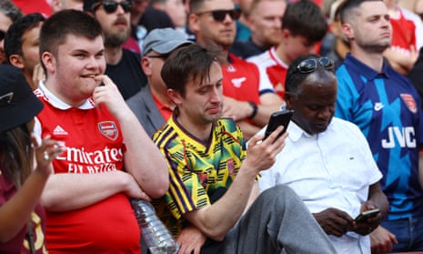 Arsenal fans check their phones in the stands at the Emirates