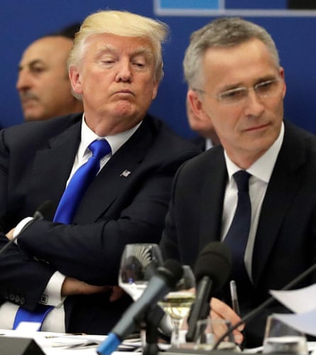 US President Donald Trump looks over the shoulder of Nato general secretary Jens Stoltenberg as they sit together at a desk with papers on it and a mic in front, May 2017