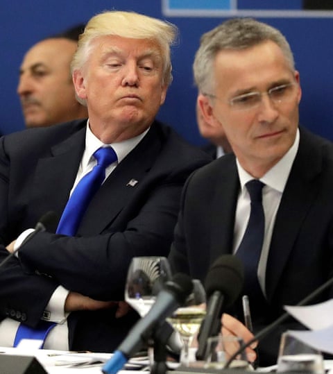 US President Donald Trump looks over the shoulder of Nato general secretary Jens Stoltenberg as they sit together at a desk with papers on it and a mic in front, May 2017