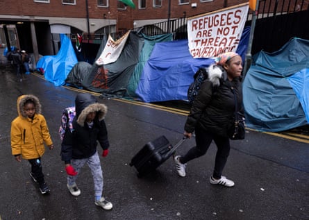 Asylum seekers walk past tents outside the International Protection Office in Dublin, Ireland.